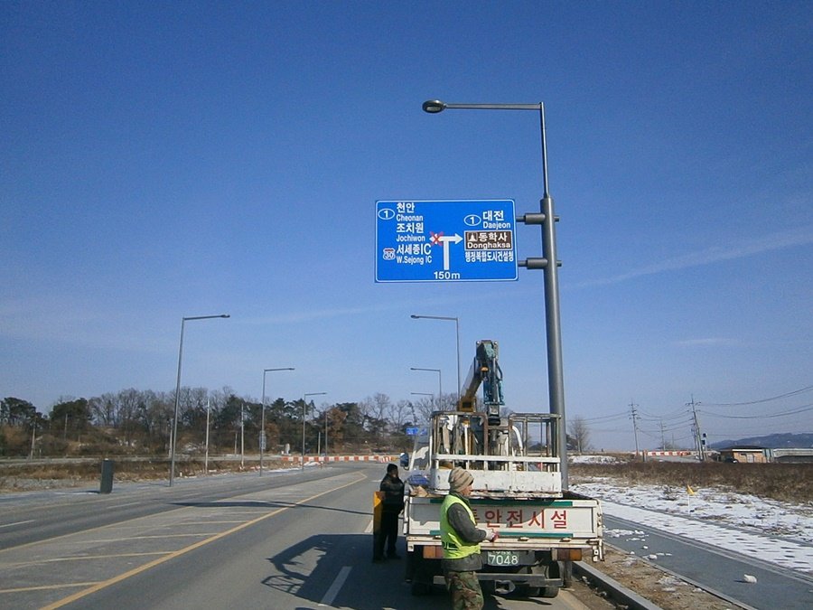 고소작업차를 이용하여 대형 도로표지판 상판을 인양하는 작업 전경
