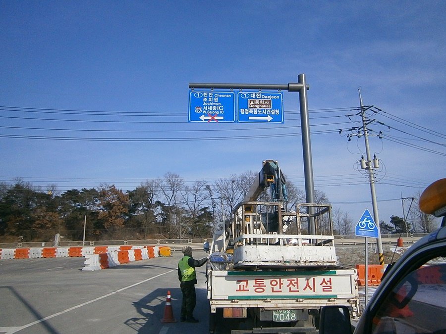 고소작업차를 이용하여 대형 도로표지판 상판을 인양하는 작업 전경