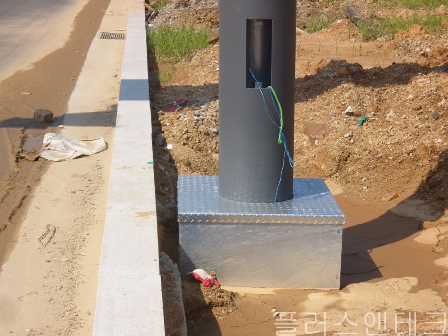 노출된 콘크리트 기초와 앵커볼트를 보호하기 위해 지주 하단에 체크무늬 강판 재질의 지주 베이스커버를 씌운 초기 공정 사진.