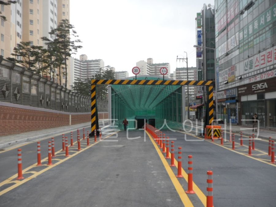 지하차도 진입로 전방에 설치되어 대형 차량의 진입을 막아내는 흑황색 사선 패턴의 거대한 문형식 통과높이제한시설 전경