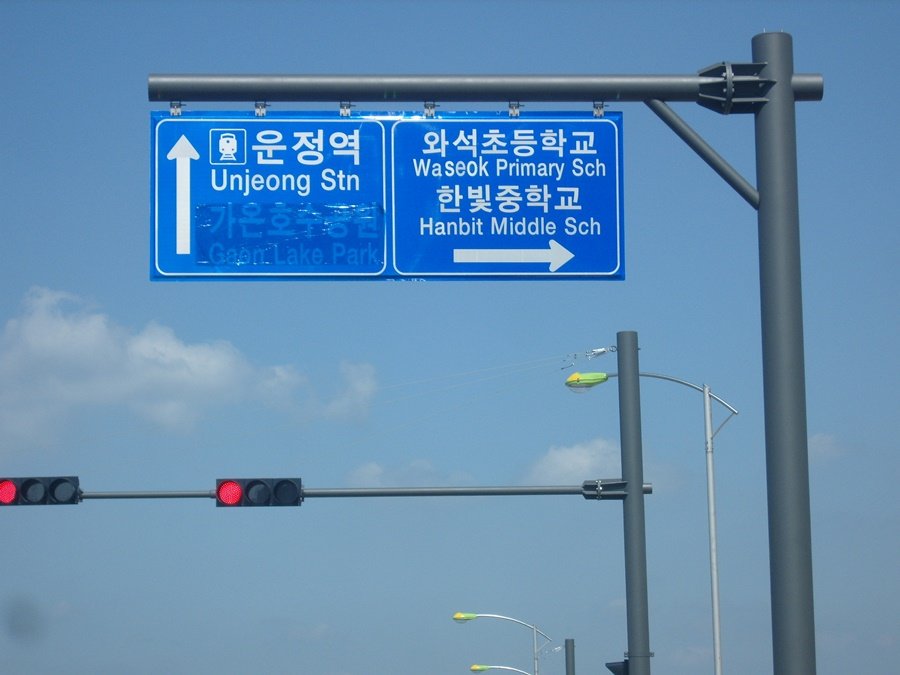 교통신호등 상단에 시인성 좋게 배치된 도로표지판과 지주 전체 외관