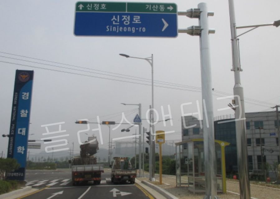 대형 크레인을 이용하여 수평 암과 표지판 패널을 정확한 위치에 결합하고 있는 편지식 지주 시공 양중 작업 전경.