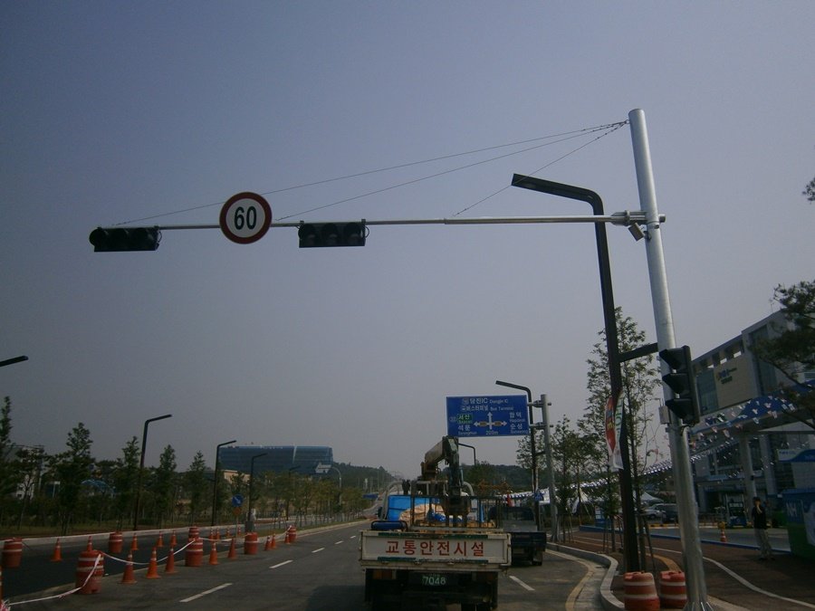 고소작업차를 배치하고 기존 신호등 철주에 신호준수 표시판을 부착하기 전 안전 통제 및 사전 점검을 진행하는 모습.