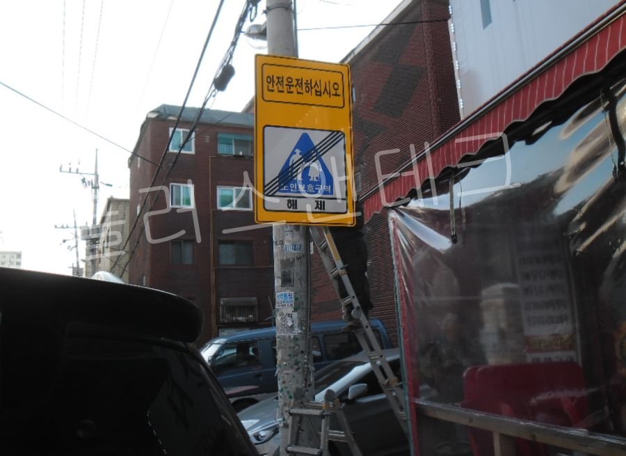 실버존 구간이 종료됨을 명확히 안내하기 위해 흑색 사선이 적용된 구역 해제 노인보호표지판 설치를 진행하는 모습.