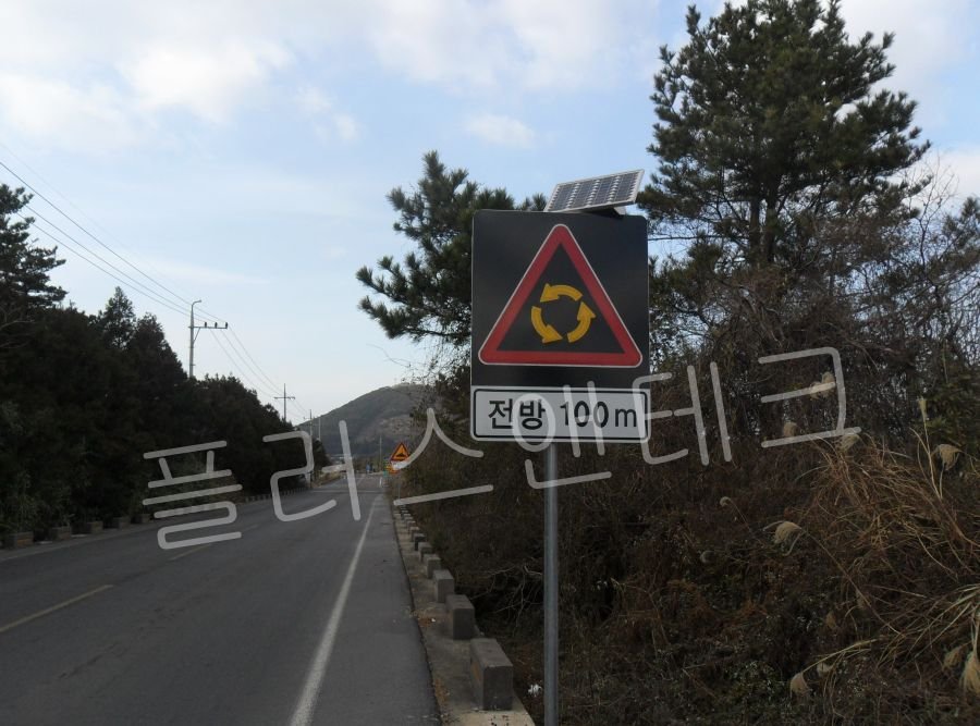 태양광 연동형 패널이 장착된 플러스앤테크 회전교차로 표지판 주간 도로 설치 전경