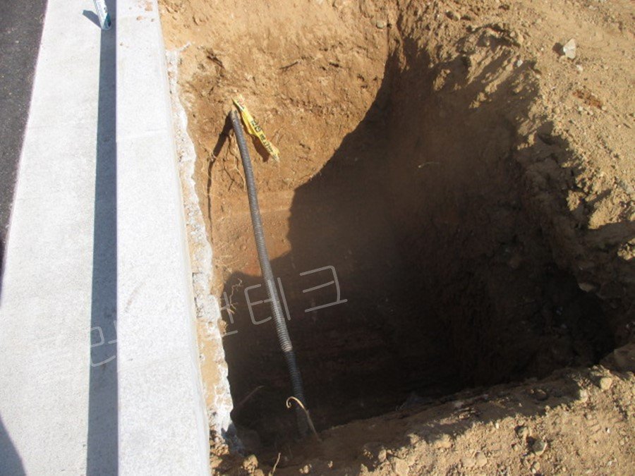  굴착된 기초 내부를 가로지르는 지하 매설 배관을 확인하고 보호 조치를 취하며 지주 설치 공간을 확보한 상세 사진