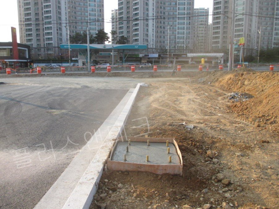 표면 미장 작업이 완료된 후 정확한 간격으로 배열된 8개의 앙카 볼트가 돌출된 채 거푸집 내부에서 굳어가고 있는 튼튼한 콘크리트 기초 양생 과정