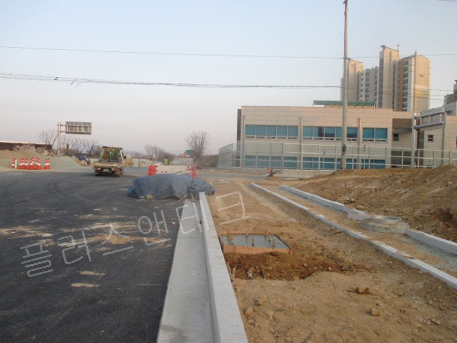 안성 복합유통단지 현장 도로변을 따라 거푸집 철거 전 충분한 양생 기간을 거치며 완성되어 가는 도로안내표지판 지주용 콘크리트 기초의 원경