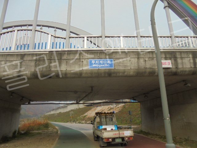 수평과 밀착도가 완벽하게 맞아떨어지게 부착 완료된 파란색 바탕의 무지개다리 교량명판 전체 샷