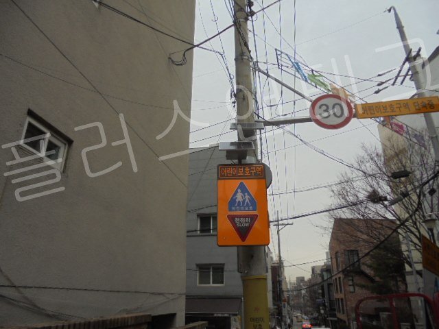 전신주에 단단히 결속된 태양광 패널과 스쿨존 표지판이 주변 전선들과 간섭 없이 깔끔하게 설치된 모습