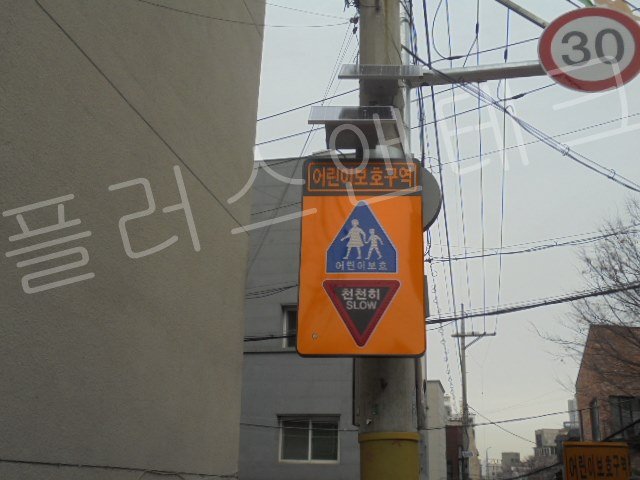 정면에서 바라본 완벽한 수직 수평을 자랑하는 어린이보호구역 천천히 SLOW 발광형 표지판 설치 완료 모습