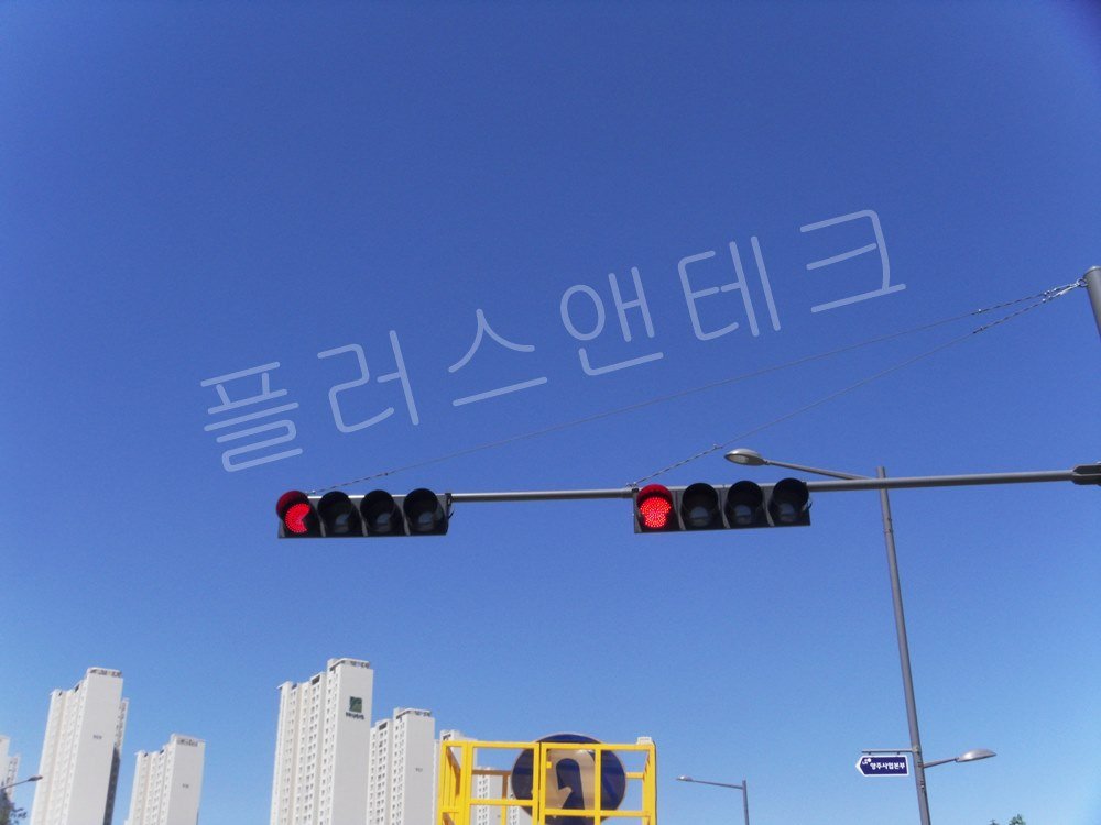 옥정중앙공원 방향 안내 도로 표지판과 나란히 배치된 LED 신호등이 교차로 상단에 균형 있게 설치된 전경