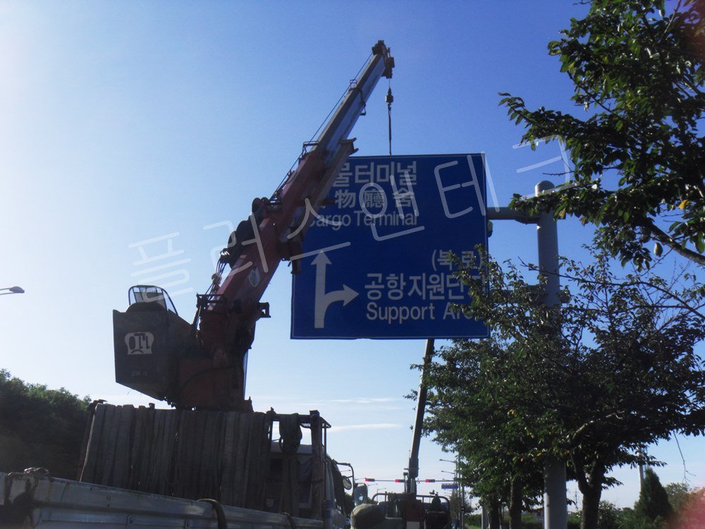 대형 카고 크레인을 동원하여 화물터미널 안내 도로표지판을 공중으로 양중하여 지주에 접근시키는 시공 장면