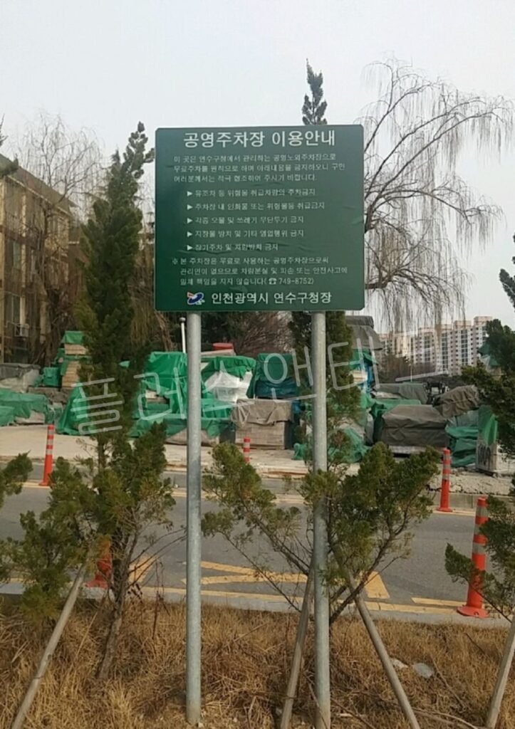 공영주차장 이용안내문과 금지사항이 명시된 대형 녹색 쌍주식 지주 표지판