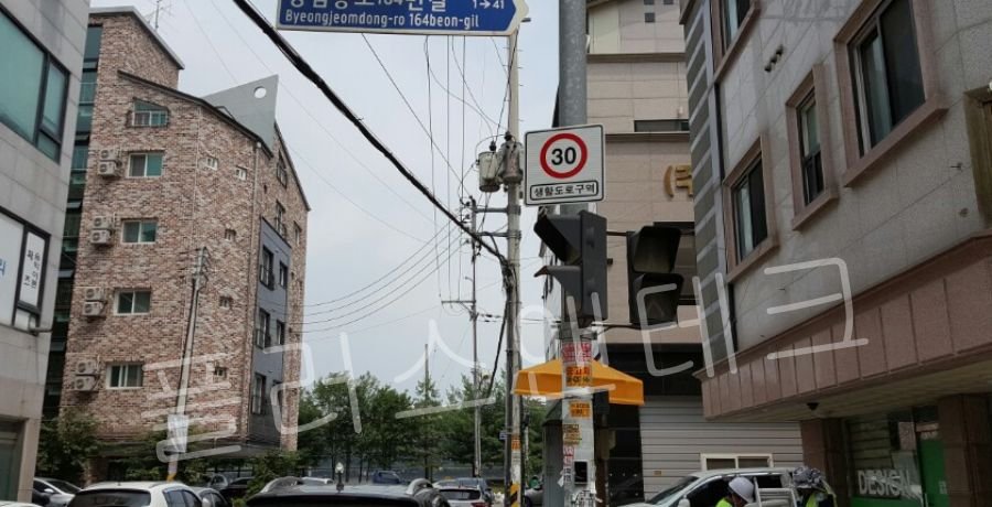 시공이 완료된 30km 제한 속도 생활도로구역 표지판과 보행자 신호등, 도로명판이 견고하게 설치된 천안 도로 교차로 전경