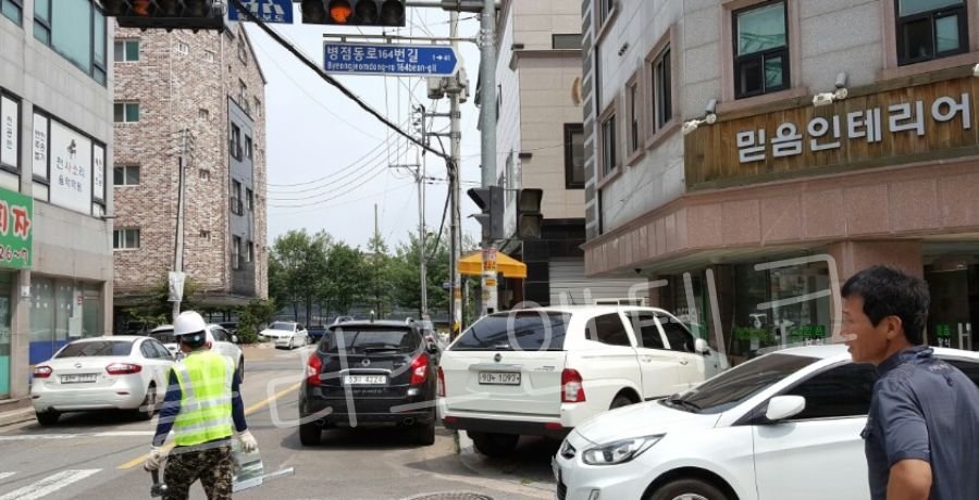 천안 생활도로구역 교차로에서 플러스앤테크 작업자들이 신호등 및 표지판 시공을 위해 차량을 통제하고 주변 안전을 확보하는 현장 모습