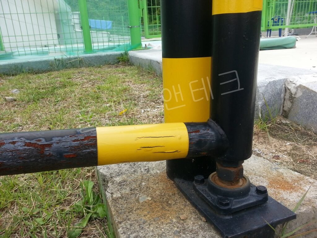 보도블록과 잔디 경계에 나란히 설치된 두 개의 차단기 지주 상단부
