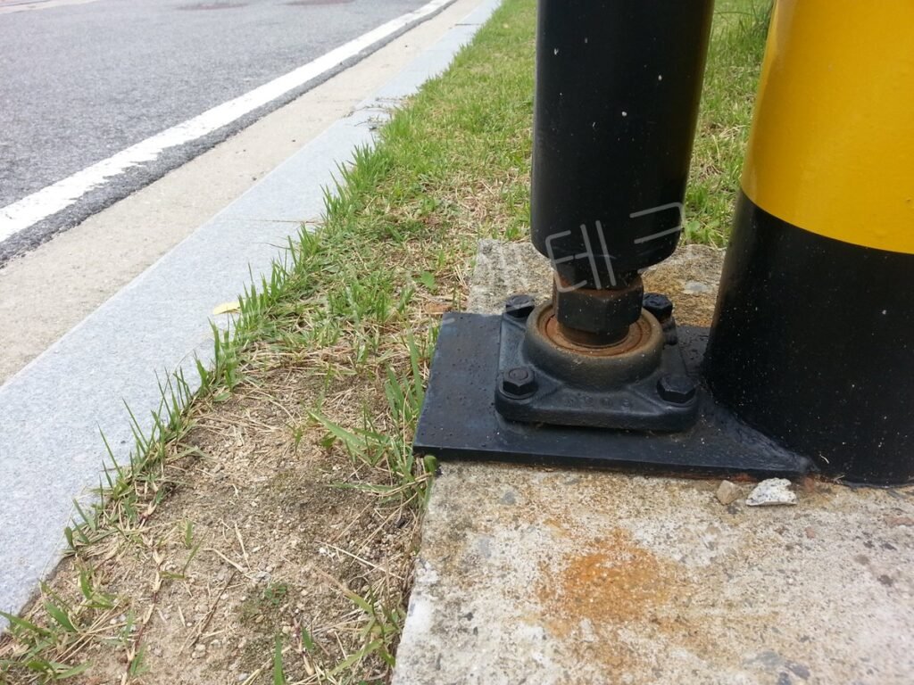 잔디밭 코너 구간에 직각으로 꺾여 설치된 차단기 펜스 연결부