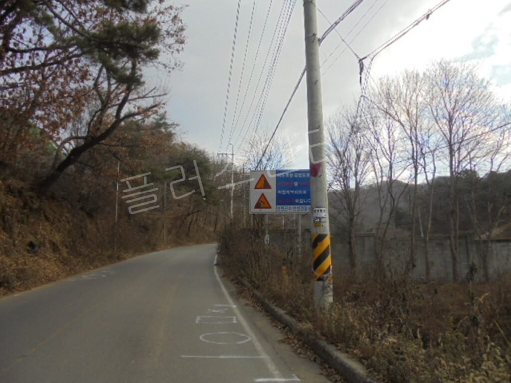 전신주에 무분별하게 부착되어 시인성이 떨어지는 기존의 낙석주의 및 결빙지역 경고 표지판 모습