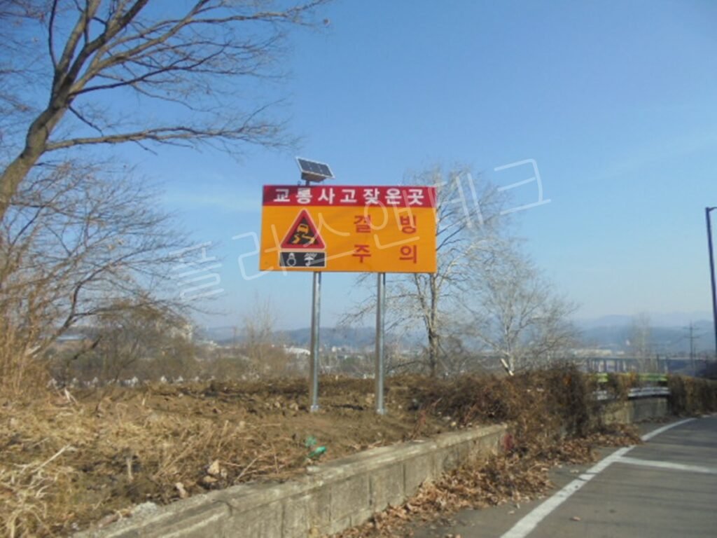 정면에서 바라본 시공 완료 사진, 파란 하늘 아래 압도적인 시인성을 자랑하는 고휘도 황색 바탕의 교통사고 잦은 곳 경고 표지판